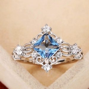 Detailed macro view of princess cut blue gemstone ring with hollow floral silver band
