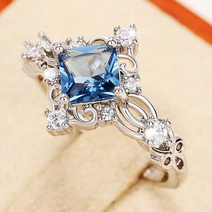 Macro shot of square blue gemstone ring with intricate vine carvings and white zircon accents