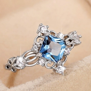 Macro shot of blue gemstone ring with intricate silver floral patterns and tiny zircons
