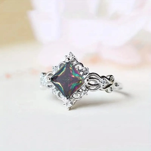 Macro shot of silver ring with square rainbow gemstone and floral hollow band