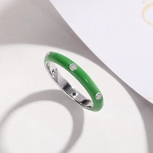 Macro detail of grass green enamel ring with inlaid white zircons on silver band