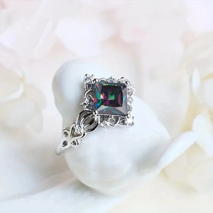 Elegant silver ring with square rainbow gemstone and diamonds on a bird stand