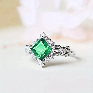 Macro view of square green gemstone ring with silver hollow floral engraving and white diamonds