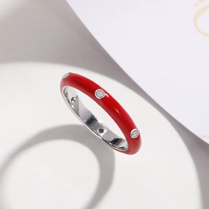 Detailed view of a red enamel ring with three sparkling inset cubic zirconia stones