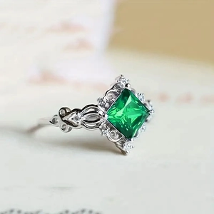 Macro detail of square emerald zircon ring with silver floral pattern and white stones