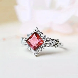 Detailed close-up of a silver ring featuring a red square gem and zircon accents