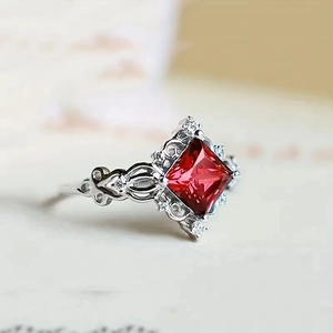 Vintage princess-cut red gemstone ring with ornate silver filigree band design