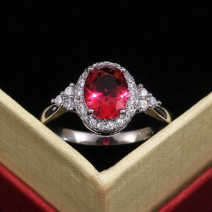 Macro d'une bague avec rubis ovale et sertissage halo de diamants dans un écrin