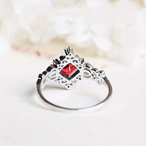 Detailed macro view of vintage silver ring with red gemstone and intricate filigree