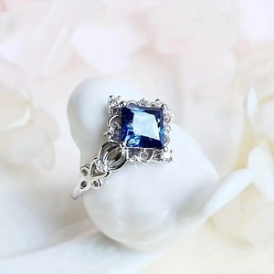 Exquisite princess style ring with large blue gemstone and diamond rhombus accents
