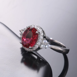 Vue macro d'une bague avec gemme rouge ovale et micro-pavage de zircons sur anneau argent