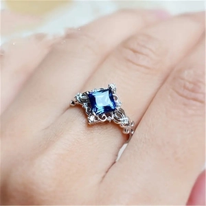 Detailed macro view of vintage princess cut blue gemstone ring with hollow silver patterns