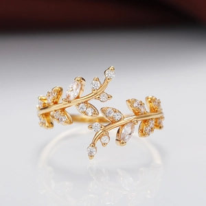 Elegante anello aperto a foglia dorata con pietre di zircone scintillanti su fondo bianco