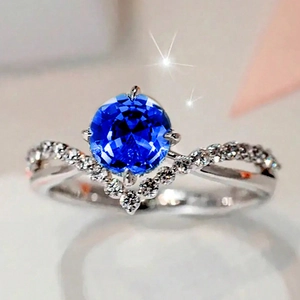 Macro shot of silver ring featuring deep blue round gemstone with V-shaped pavé accents