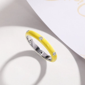 Detail of yellow enamel ring featuring three inlaid zircons on a silver-toned metal band