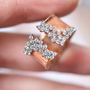 Macro shot of rose gold wide band ring with brushed texture and cubic zirconia accents