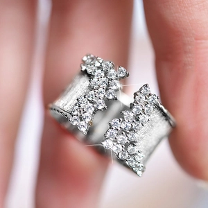 Macro shot of silver wide open ring featuring brushed metal finish and pave zircon setting