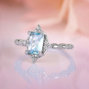 Elegant silver crown ring with emerald-cut blue gemstone and vintage engraved lace band