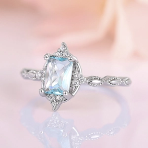 Detail showing an emerald-cut light blue gemstone on a silver vintage ring with side diamonds
