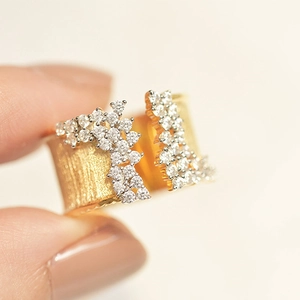 Macro shot of gold-plated wide open ring with hammered texture and pave-set zircons