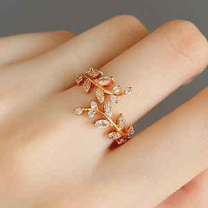 Elegante anello a foglia d'oro con pietre di zircone bianco su mano femminile
