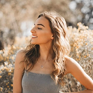 Close-up of heart and cross pendant necklace worn by a model in natural sunlight