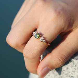 Détail macro d'une bague en or avec émeraude ronde et diamants latéraux marquise