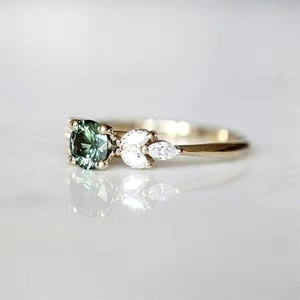 Gros plan d'une bague dorée vintage avec émeraude ronde et diamants en forme de feuille