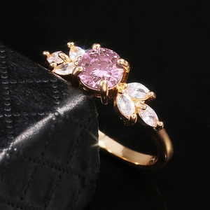 Détail macro d'une bague en or avec gemme ronde rose et pétales de diamants marquise