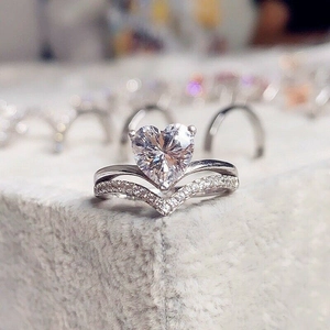 Detailed macro view of heart-cut crystal ring with micro-paved V-shaped silver band
