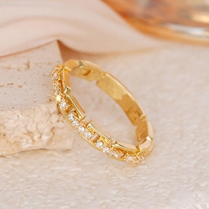 Detail eines goldfarbenen Kettengliedrings mit weißen Zirkonia auf Seide und Stein