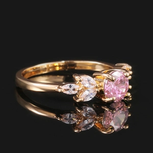 Détail macro d'une bague avec pierre rose et pierres marquises sur fond noir réfléchissant