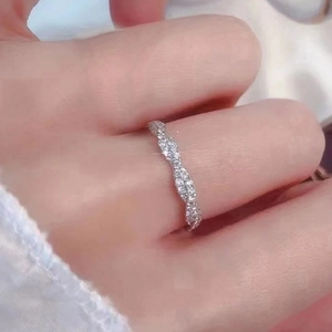 Detail eines gedrehten Silberrings mit glitzernden Steinen am Finger einer Frau