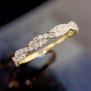 Makro-Detail des goldenen gedrehten Ringes mit Pavé-Kristallen auf dunklem Grund