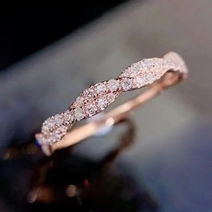 Makroaufnahme von roségoldenem Ring mit gedrehtem Band und weißem Zirkonia-Besatz