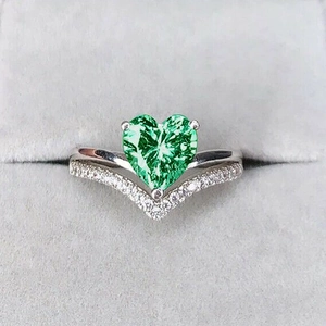 Close-up of heart-shaped green gemstone ring with pavé v-shaped band in velvet box