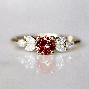 Vue détaillée d'une bague en or avec rubis rouge central et pierres en forme de feuilles