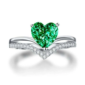 Macro detail of V-shaped silver ring featuring a green heart emerald and diamond pavé