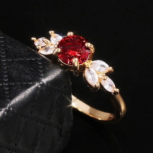 Détail macro d'une bague dorée avec pierre rouge ronde et accents en zircon de forme marquise