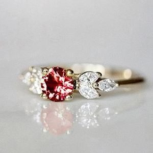 Vue macro d'une bague dorée avec pierre rouge ronde et pierres blanches en forme de feuille