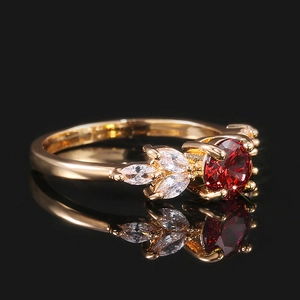 Gros plan d'une bague dorée avec un gros rubis rouge et des zircons marquises