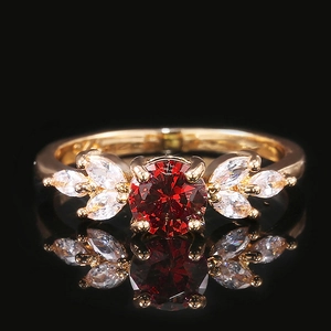 Détail d'une bague avec pierre rouge et pierres latérales sur miroir noir poli
