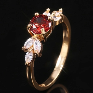 Détail d'une bague dorée avec pierre ronde rouge et pierres latérales de taille marquise