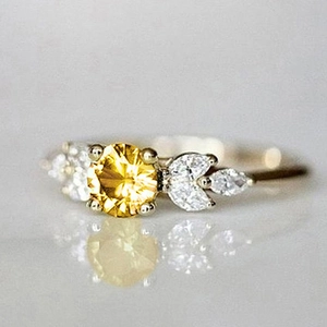 Macro d'une bague en argent avec pierre jaune ronde et pierres latérales marquise