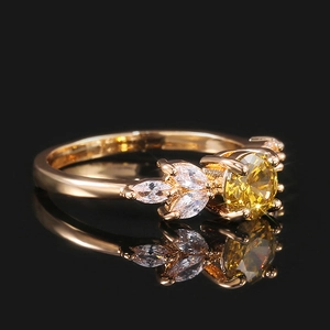 Gros plan d'une bague dorée avec zircon jaune et pierres marquise sur miroir noir