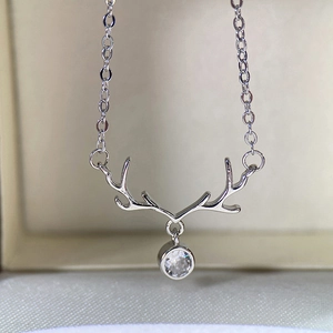 Macro shot of a silver reindeer antler pendant necklace with a brilliant round zircon stone