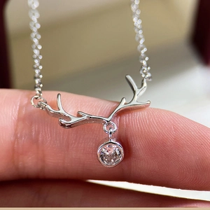 Macro shot of silver reindeer antler pendant with a round zircon stone on a cross chain