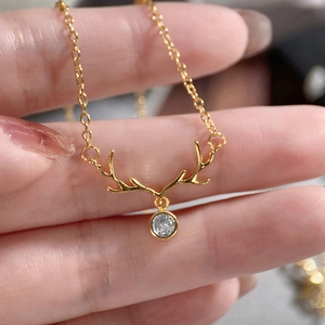 Macro shot of gold reindeer antler necklace featuring a clear round zircon pendant detail