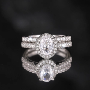 Makroaufnahme von ovalem Halo-Verlobungsring-Set mit Pavé-Band auf schwarzem Reflex