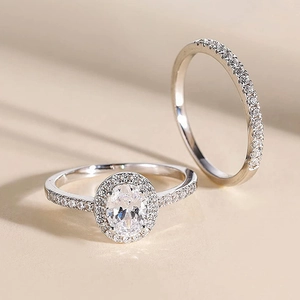 Makro-Detail des silbernen Oval-Halo-Ring-Sets mit Mikro-Pave-Steinen auf warmem Grund